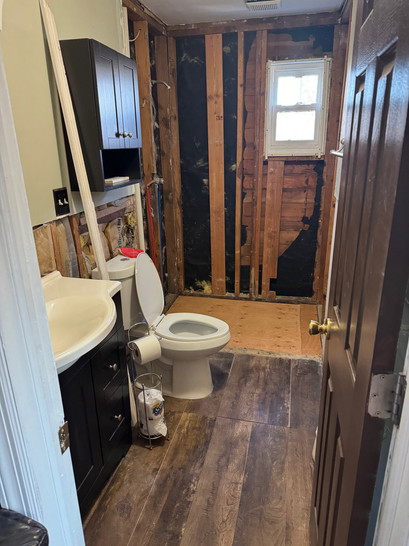 A bathroom with wooden floors and a toilet.