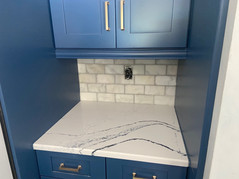 A kitchen with blue cabinets and a marble countertop.