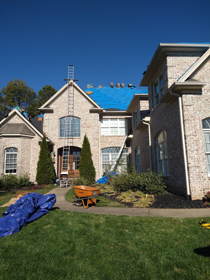 A spacious house with a blue tarp covering it.