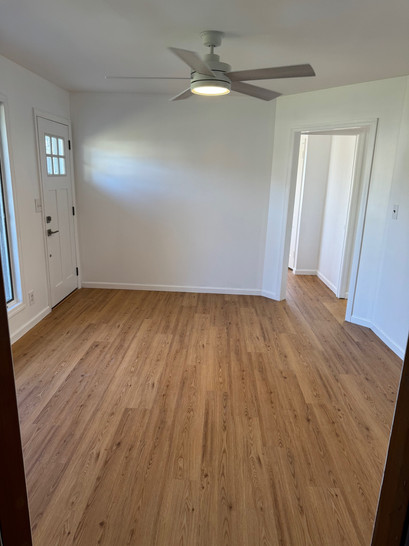 An empty room with hardwood floors and a ceiling fan.